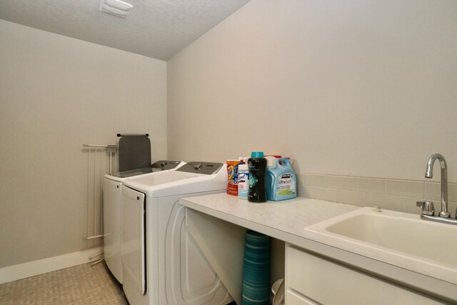 laundry room with laundry area, baseboards, a textured ceiling, separate washer and dryer, and a sink