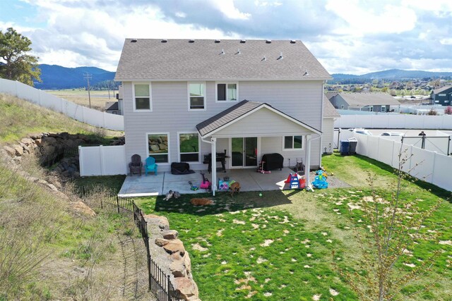 back of property with a yard, a fenced backyard, a mountain view, and a patio area