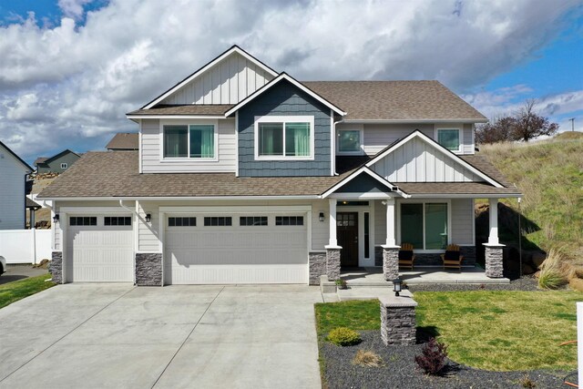 craftsman-style house featuring stone siding, board and batten siding, covered porch, and driveway