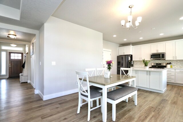 dining space featuring baseboards, recessed lighting, light wood finished floors, and a notable chandelier