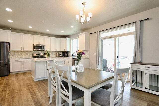dining room with recessed lighting, light wood-type flooring, and a chandelier