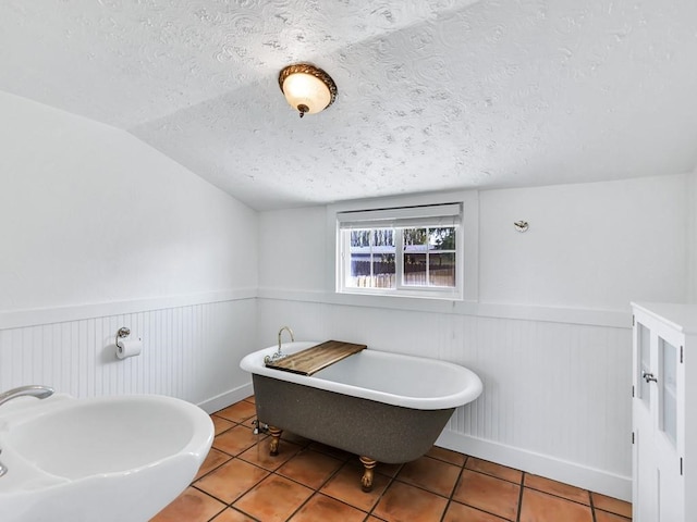 610 Ross St, Davenport, WA 99122 - full bathroom with a textured ceiling, vaulted ceiling, tile patterned floors, and a wainscoted wall
