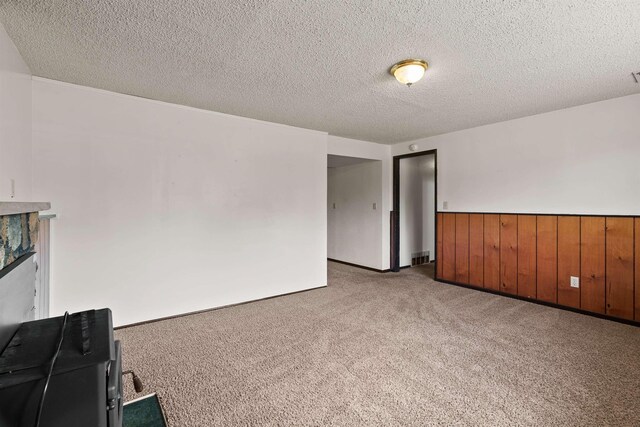 1317 S Woodlawn Rd, Spokane Valley, WA 99216 - unfurnished living room with wooden walls, a wainscoted wall, carpet, and a textured ceiling