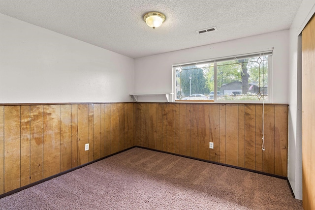 1317 S Woodlawn Rd, Spokane Valley, WA 99216 - carpeted empty room with visible vents, a textured ceiling, wainscoting, and wooden walls