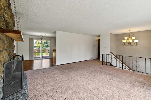 1317 S Woodlawn Rd, Spokane Valley, WA 99216 - unfurnished living room featuring a fireplace, carpet floors, a textured ceiling, a chandelier, and visible vents