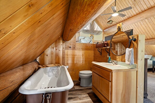 full bathroom with wood ceiling, a freestanding bath, wood walls, toilet, and vaulted ceiling with beams