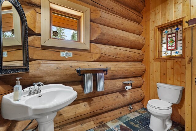 half bathroom with wood walls, rustic walls, and toilet