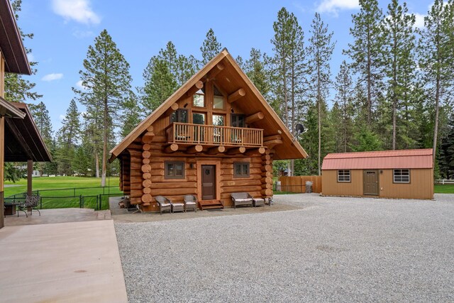 back of property featuring fence, log siding, and a balcony