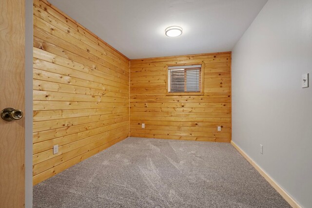 unfurnished room featuring wooden walls and carpet