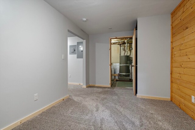 carpeted spare room with baseboards, electric panel, and secured water heater