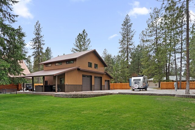 rear view of house featuring fence, a covered hot tub, metal roof, a yard, and gravel driveway