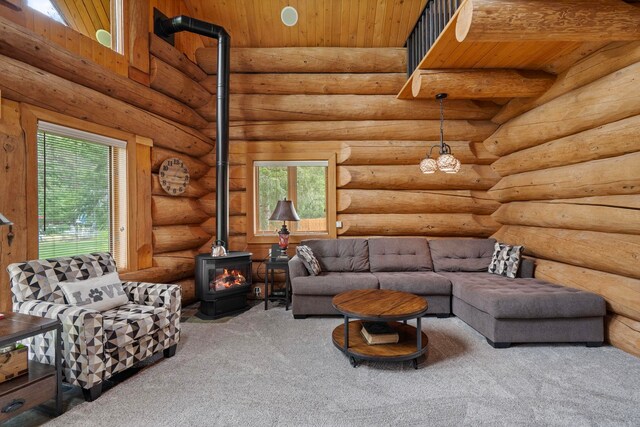 living area with carpet floors, a wood stove, and wood ceiling