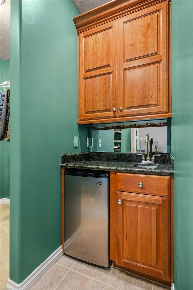 1909 E Pinecrest Rd, Spokane, WA 99203 - kitchen with dishwashing machine, a sink, brown cabinetry, baseboards, and light tile patterned flooring