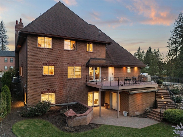 1909 E Pinecrest Rd, Spokane, WA 99203 - back of property at dusk featuring brick siding, a wooden deck, a chimney, and a patio