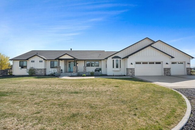 single story home featuring board and batten siding, a front lawn, concrete driveway, an attached garage, and stone siding