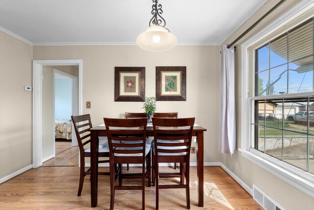 dining room with crown molding, baseboards, wood finished floors, and visible vents
