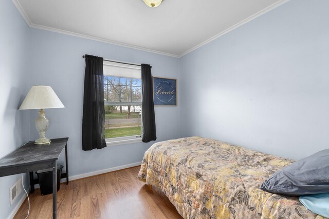 bedroom featuring baseboards, ornamental molding, and wood finished floors