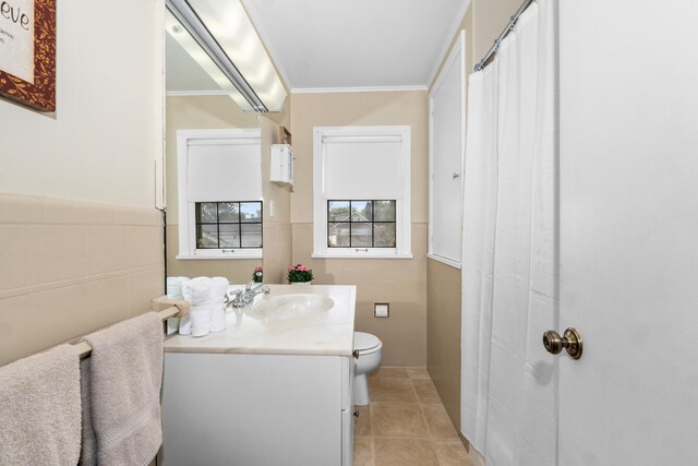 bathroom featuring crown molding, wainscoting, vanity, toilet, and tile walls