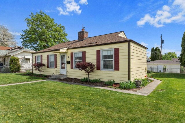 view of front of property featuring fence, a chimney, and a front lawn