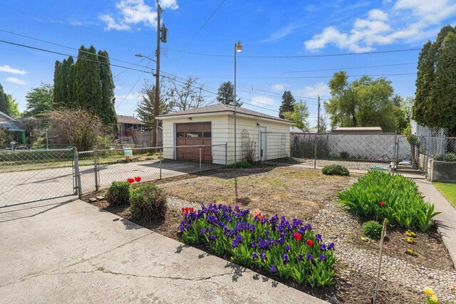 view of yard featuring fence, a gate, concrete driveway, an outbuilding, and a detached garage