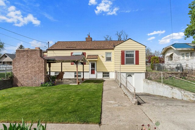 view of front of home with a patio, a front lawn, fence, and a chimney