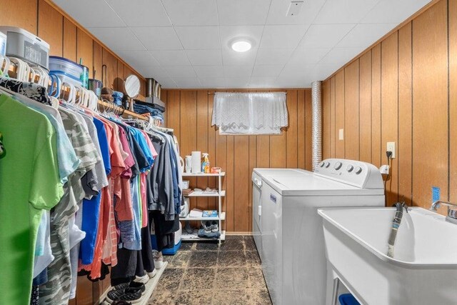 laundry area featuring separate washer and dryer, laundry area, wood walls, and a sink
