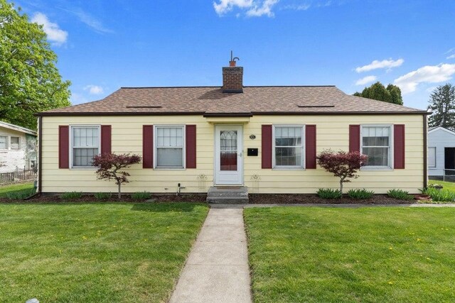 view of front of property with fence, a front yard, and a chimney