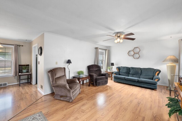 living area with light wood-style floors, ceiling fan, ornamental molding, and visible vents