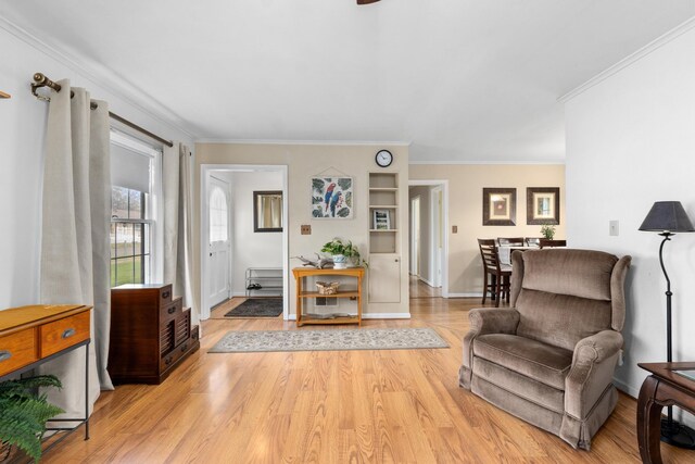 living area featuring baseboards, ornamental molding, and light wood-type flooring
