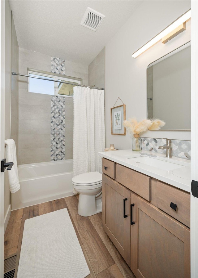 bathroom with shower / tub combo with curtain, vanity, toilet, wood finished floors, and visible vents