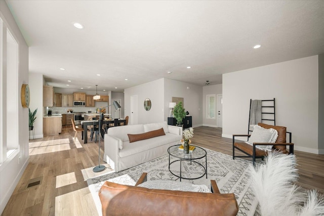 living room with recessed lighting, light wood-style floors, and baseboards