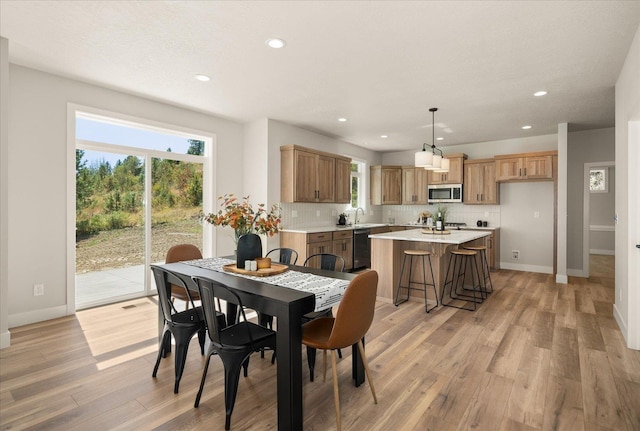 kitchen featuring light wood-type flooring, a sink, decorative backsplash, and appliances with stainless steel finishes