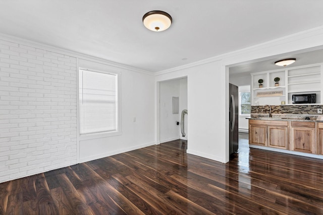 5804 N Regal St, Spokane, WA 99208 - unfurnished living room with crown molding, a sink, brick wall, baseboards, and dark wood-type flooring