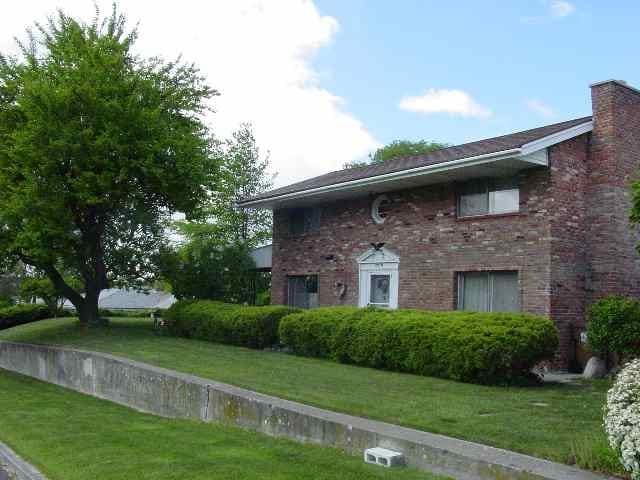 view of home's exterior featuring a lawn, brick siding, and a chimney