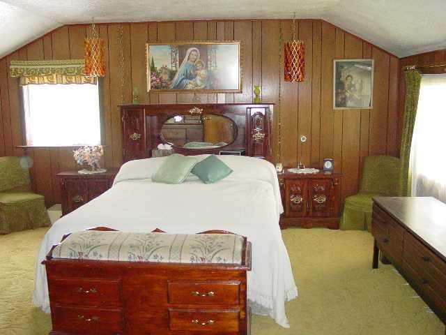 carpeted bedroom featuring wooden walls, multiple windows, and vaulted ceiling