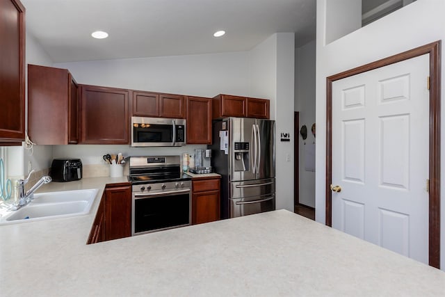 kitchen featuring appliances with stainless steel finishes, vaulted ceiling, a sink, light countertops, and recessed lighting