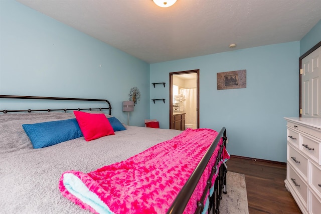 bedroom with ensuite bathroom, dark wood finished floors, and baseboards
