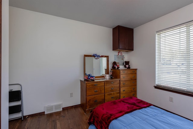 bedroom featuring baseboards, visible vents, wood finished floors, and heating unit