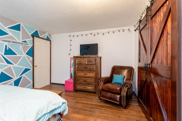 bedroom with a barn door and hardwood / wood-style floors