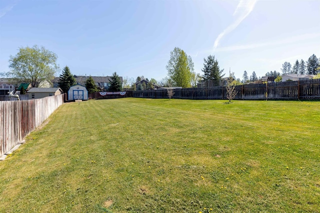 view of yard with an outdoor structure, a fenced backyard, and a shed