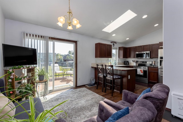 living room featuring dark wood-type flooring, a notable chandelier, lofted ceiling with skylight, and a wealth of natural light