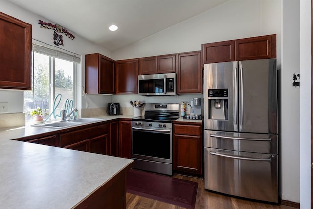 kitchen featuring appliances with stainless steel finishes, vaulted ceiling, a sink, light countertops, and dark wood-type flooring