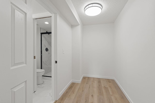 1111 W 6th Ave # 205, Spokane, WA 99204 - hallway featuring baseboards, a textured ceiling, and light wood-type flooring