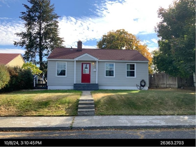 view of front of home featuring a chimney, fence, and a front yard