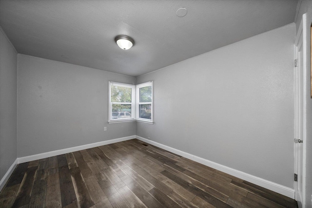 spare room featuring baseboards and dark wood finished floors