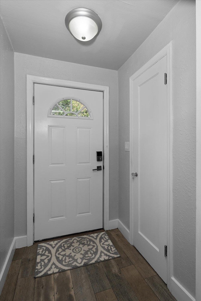 doorway featuring baseboards and wood finished floors