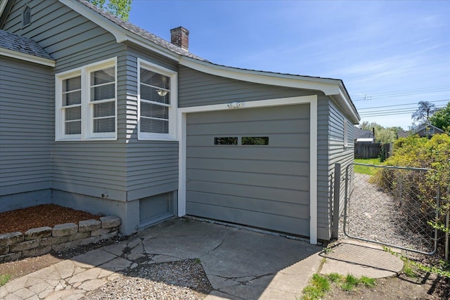 view of home's exterior with fence, a chimney, an attached garage, and driveway