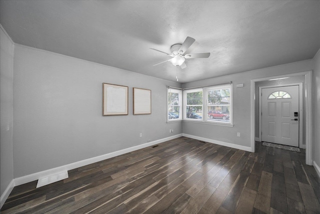 unfurnished room with a ceiling fan, baseboards, and dark wood-type flooring