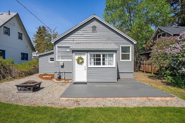 rear view of property featuring an outdoor fire pit, fence, and a wooden deck