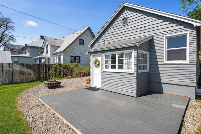 rear view of property featuring fence, a wooden deck, and an outdoor fire pit